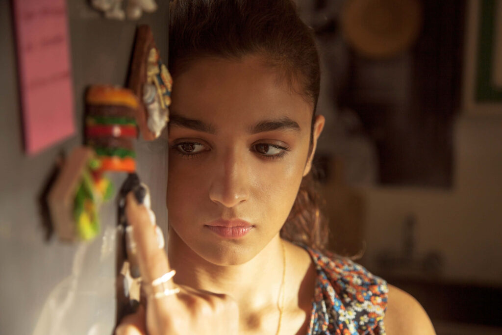 Alia Bhatt touches colorful magnet on fridge in warm sunlight with thoughtful expression wallpaper background