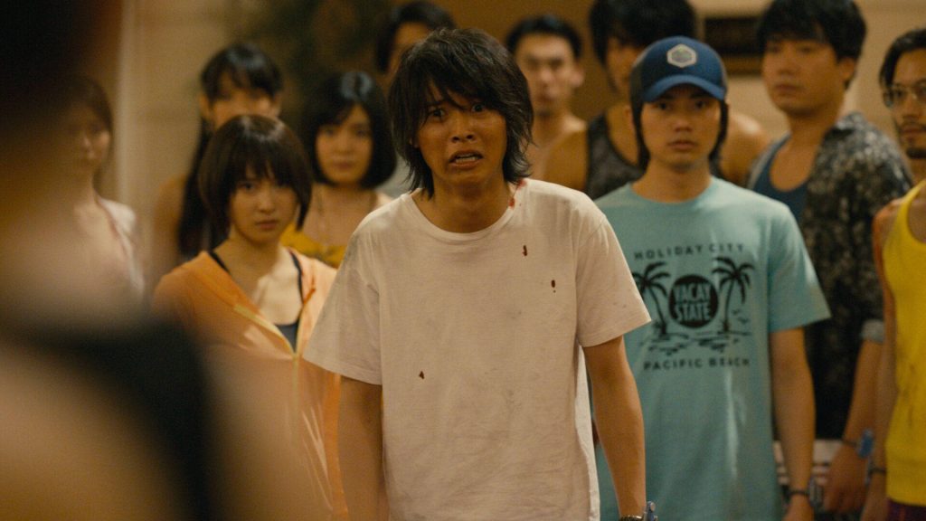 Arisu in blood-spattered white tee tense in dim crowded room Netflix Alice in Borderland wallpaper