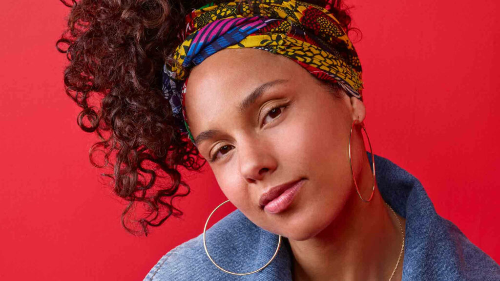 Alicia Keys confident natural style colorful patterned hairband large hoop earrings red background Wallpaper