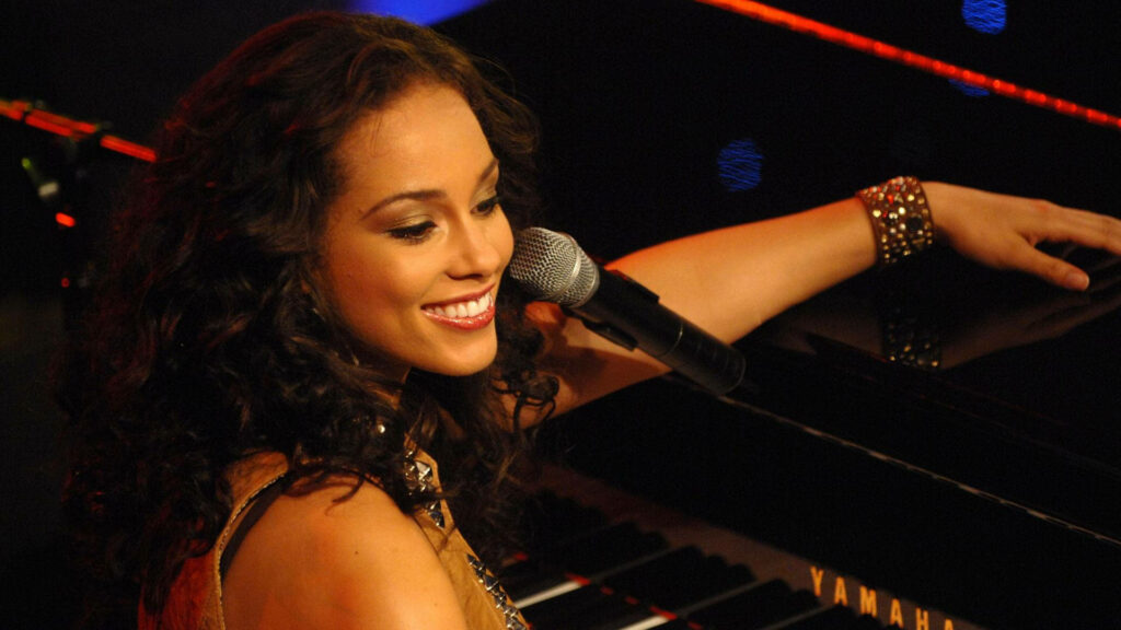 Alicia Keys performing soulful piano with warm stage lighting and engaging smile wallpaper
