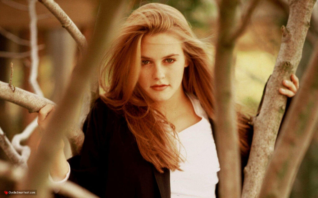 Alicia Silverstone fierce intense look flowing hair amidst tree branches bold confident wallpaper