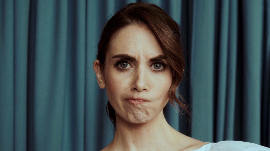 Alison Brie playful wacky facial expression wallpaper with blue curtain background vibrant design