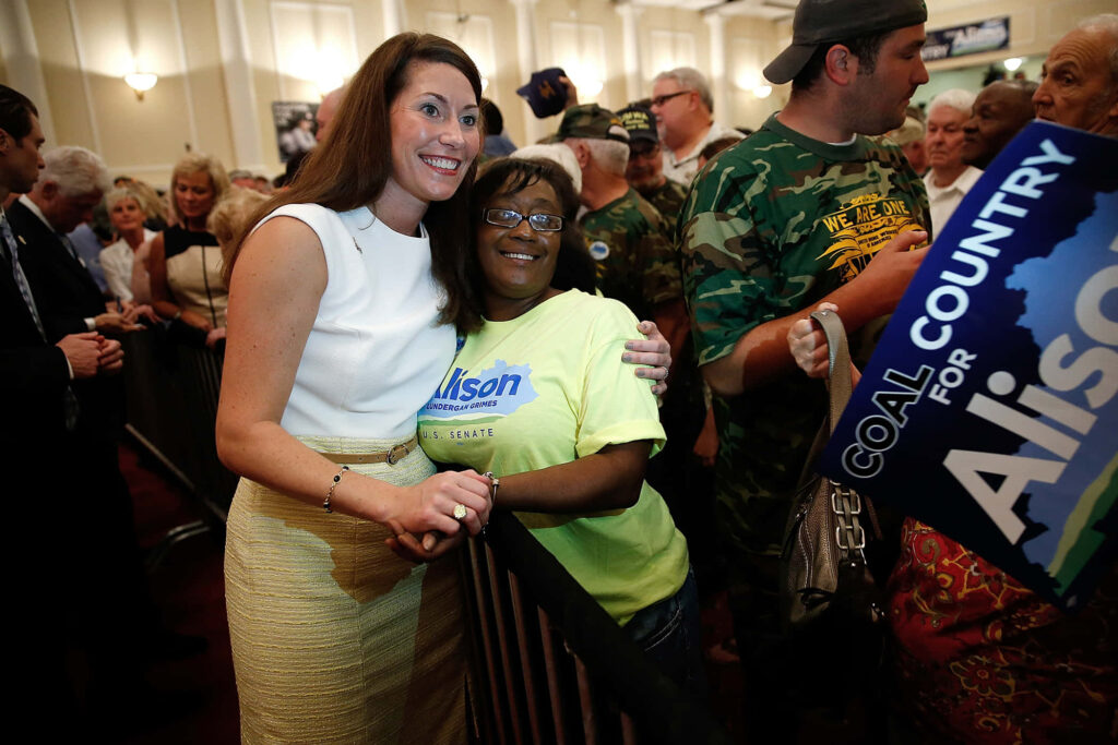 Alison Lundergan Grimes warmly hugging supporter at crowded campaign event showing enthusiasm Wallpaper
