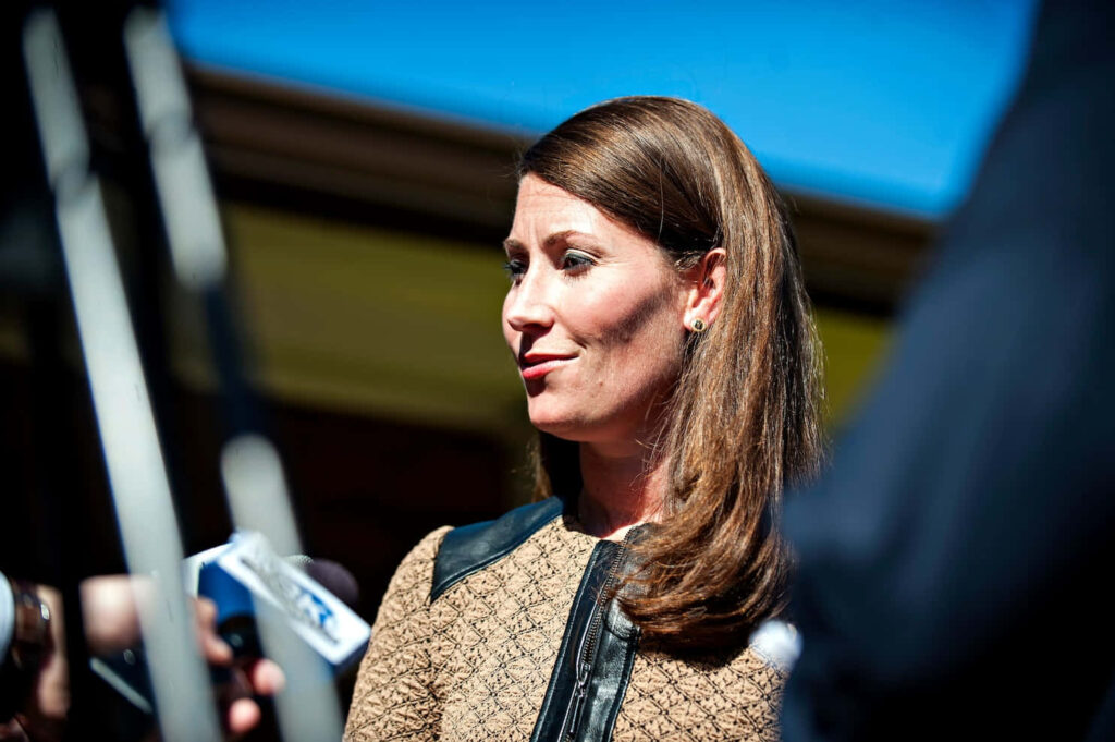 Alison Lundergan Grimes speaking to reporters outdoors with microphones and blue sky background Wallpaper