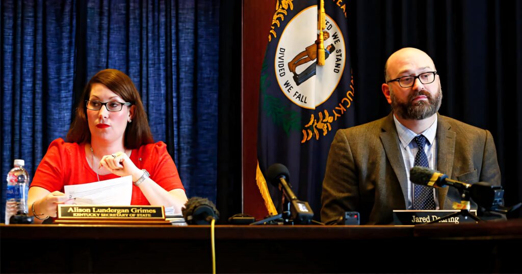 Alison Lundergan Grimes and Jared Dearing speak at press conference with Kentucky state flag backdrop Wallpaper