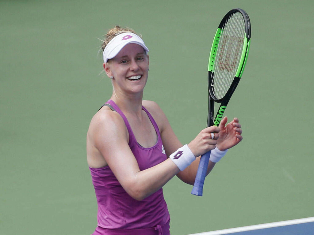 Alison Riske-Amritraj smiling on tennis court holding racket wearing athletic attire green background Wallpaper
