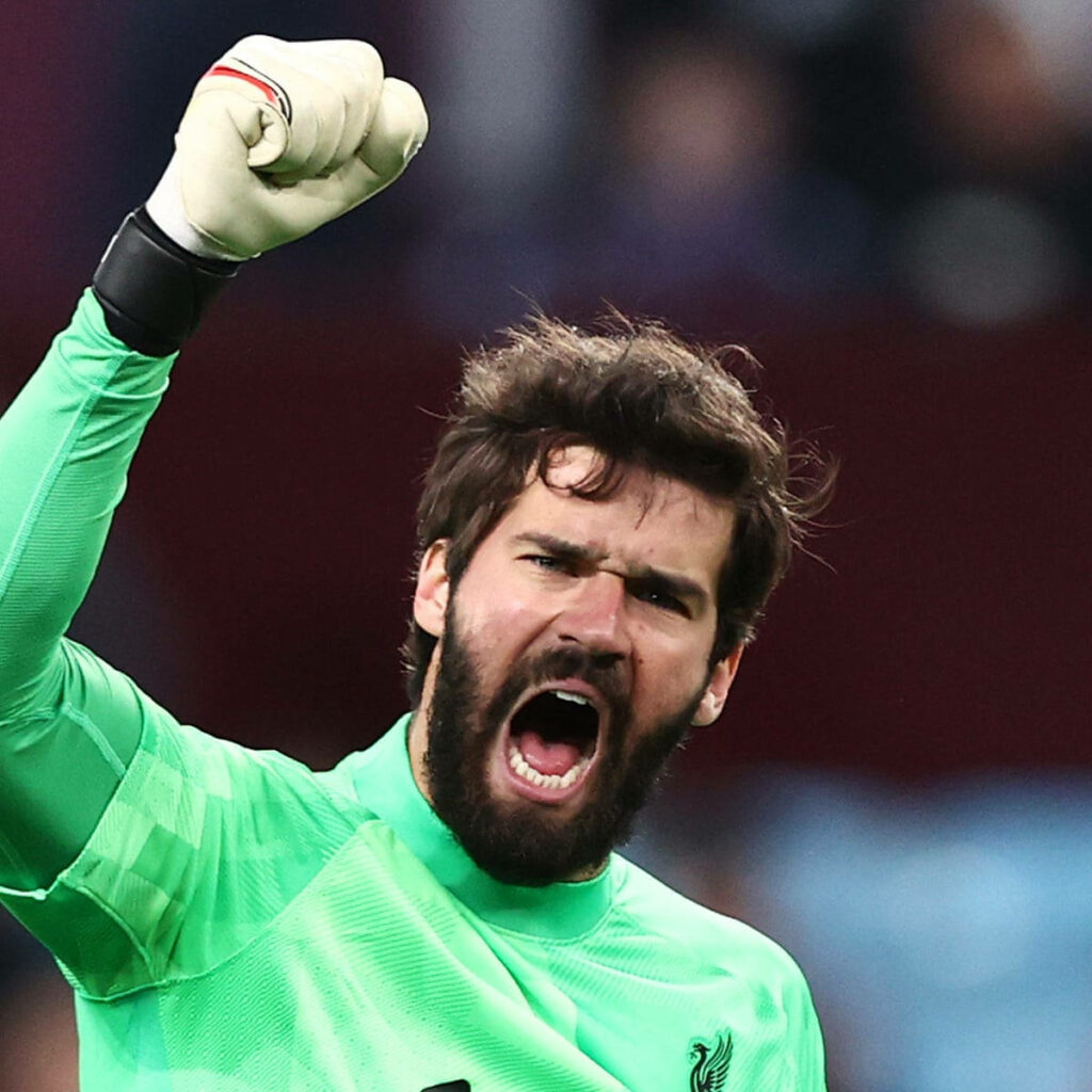 Alisson Becker celebrating passionately with fist raised on football field dynamic wallpaper background