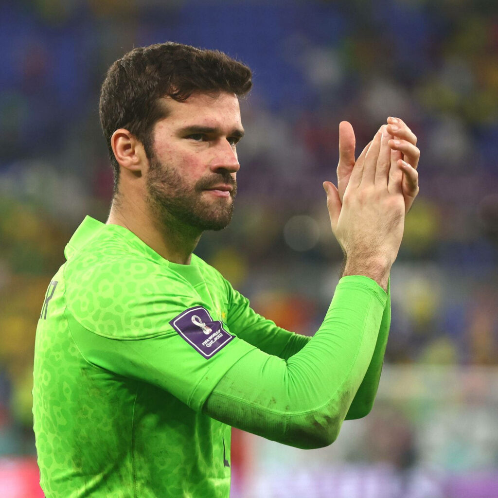 Alisson Becker clapping in green goalkeeper kit with blurred stadium background dynamic wallpaper