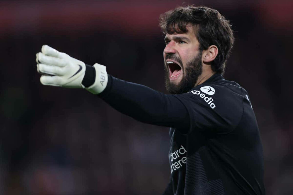 Alisson Becker focused goalkeeper passionately directing teammates on the soccer field wallpaper background