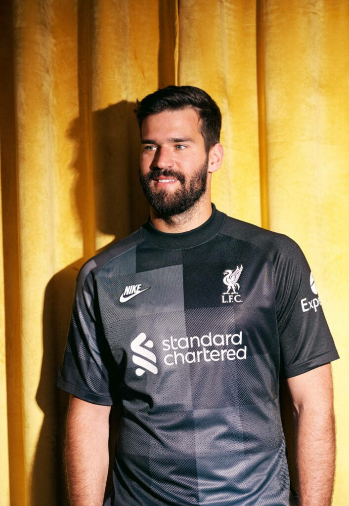 Alisson Becker Liverpool goalkeeper in red kit with bright yellow background wallpaper