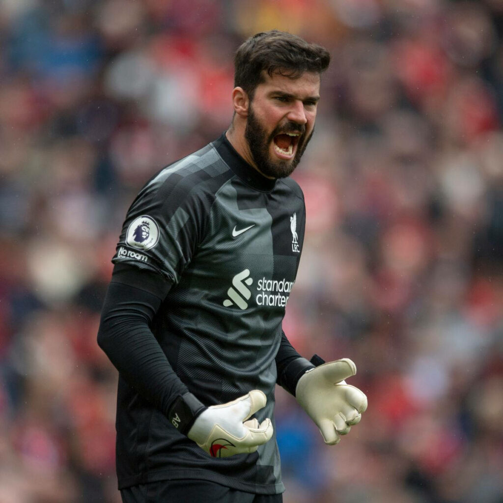 Alisson Becker celebrates passionately in Liverpool goalkeeper kit on football pitch intense moment Wallpaper