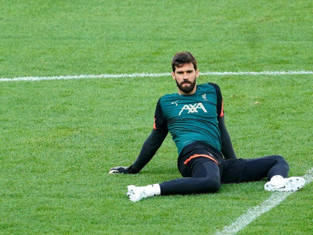 Alisson Becker resting on green football field in training kit during practice session wallpaper