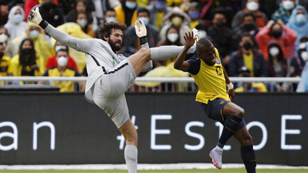 Alisson Becker and Enner Valencia collide mid air in intense football match action wallpaper background