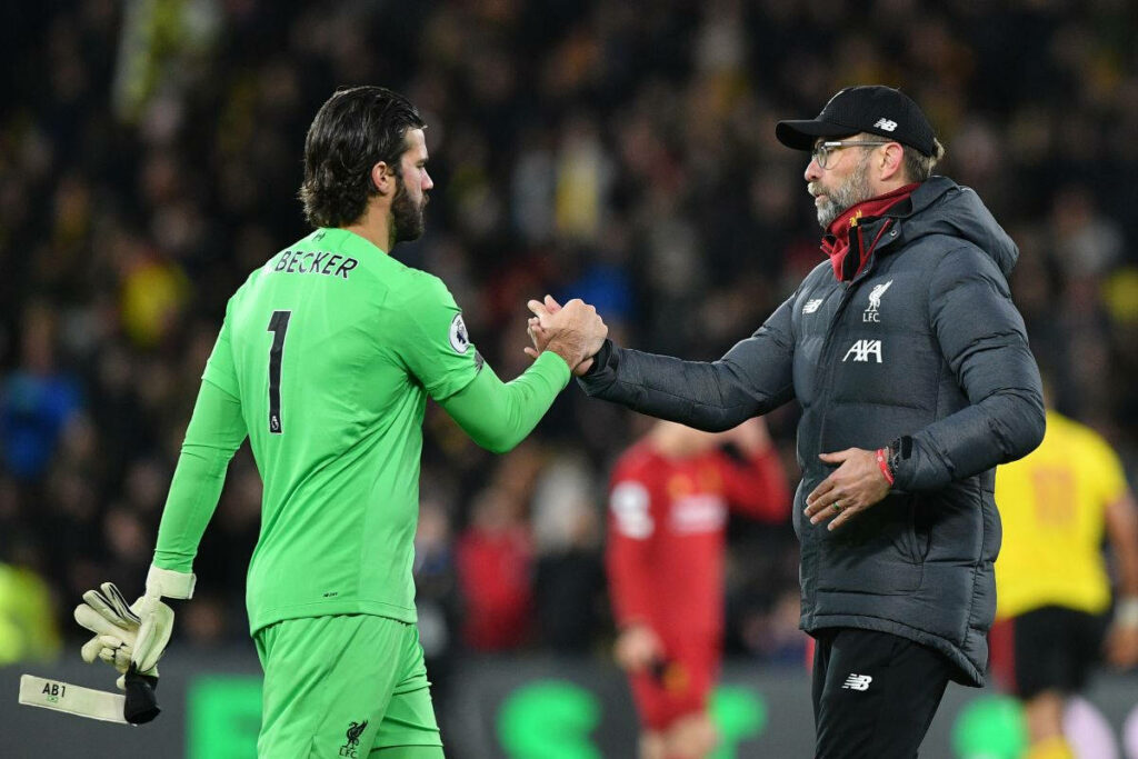 Alisson Becker and Jurgen Klopp handshake on Liverpool football field showing team unity and spirit Wallpaper