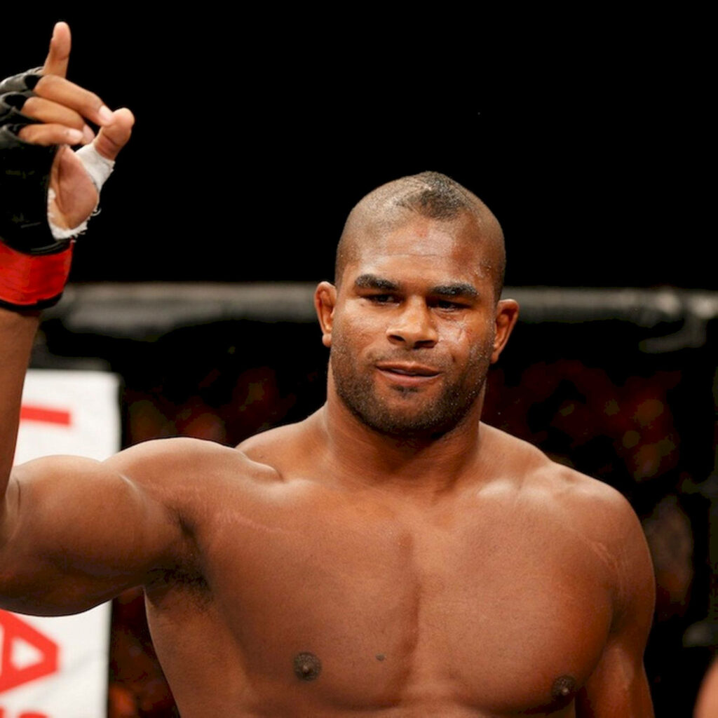 MMA fighter Alistair Overeem in ring pointing upward with determined expression wallpaper background