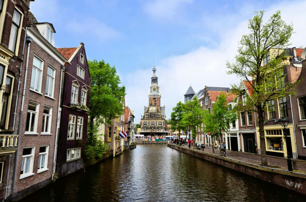 Scenic Alkmaar canal with traditional Dutch houses and historic tower in picturesque city view Wallpaper