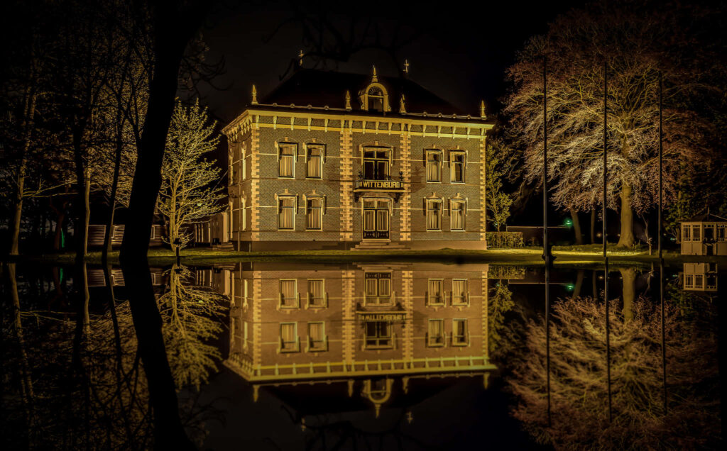 Historic Alkmaar building illuminated at night reflected in calm water serene wallpaper background