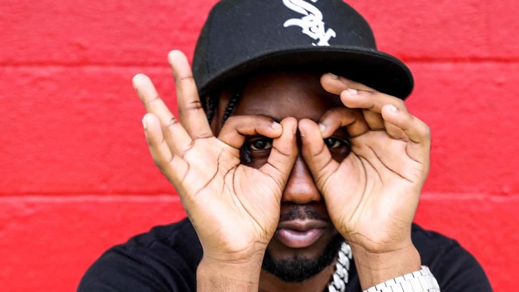 Allen Davis creator of the viral Griddy dance in black shirt and White Sox cap on red wall Wallpaper