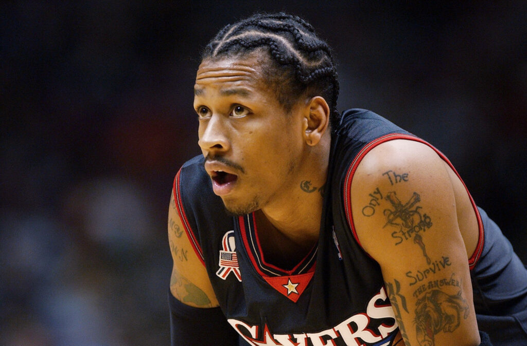 Allen Iverson crouching focused in Philadelphia Sixers jersey game day intense basketball action Wallpaper