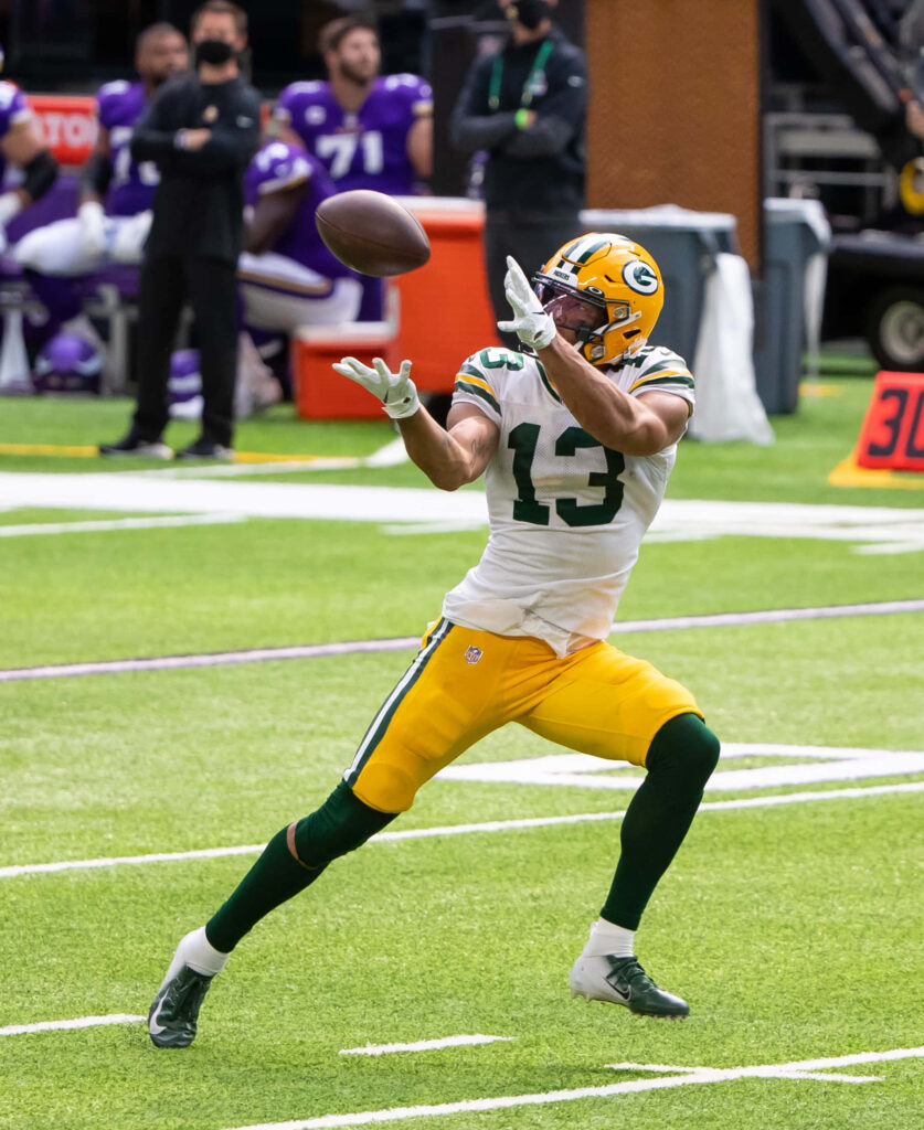 Allen Lazard stretches to catch a football during an intense Green Bay Packers game action shot Wallpaper