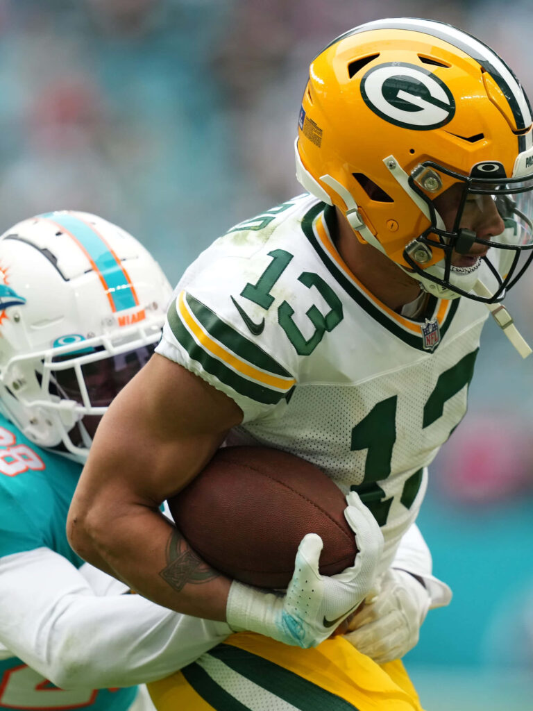 Allen Lazard in Green Bay Packers uniform evading Miami Dolphins defender in football game Wallpaper