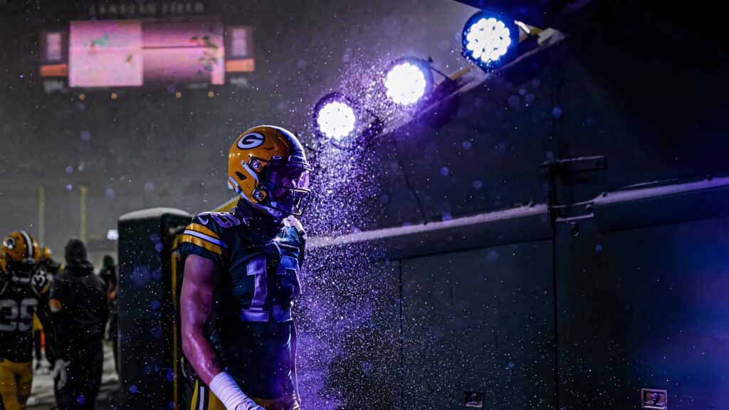 Allen Lazard on snowy football field under bright stadium lights winter night game intensity wallpaper