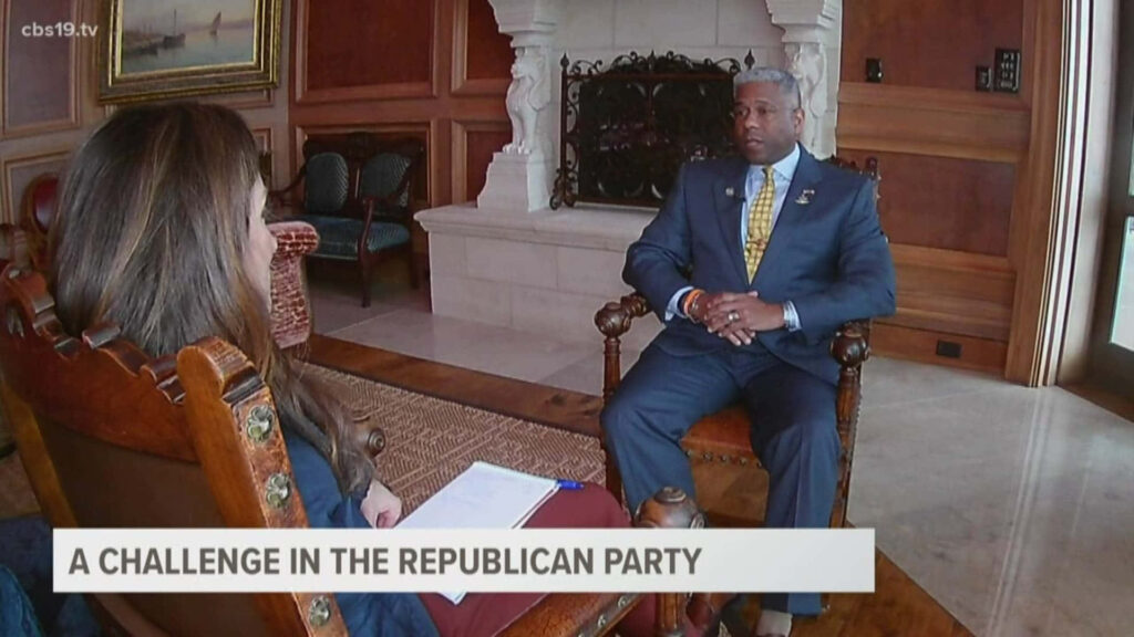 Allen West television interview discussing Republican Party challenges in elegant room with wallpaper