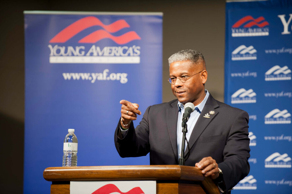 Allen West speaking at Young Americas Foundation event podium with branded banners background Wallpaper