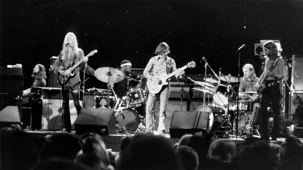 Grayscale Allman Brothers Band live concert wallpaper showing members playing instruments on stage
