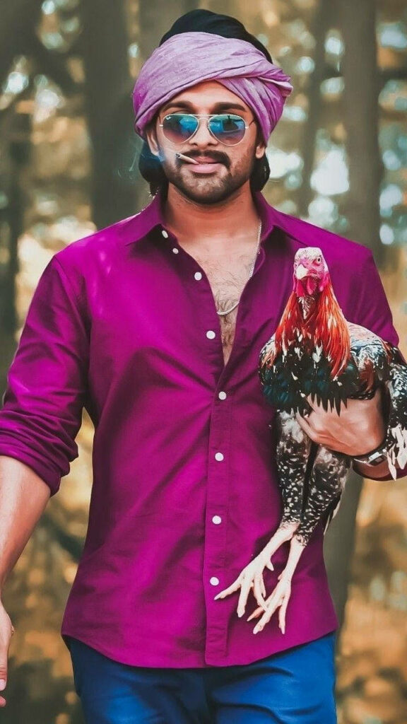 Allu Arjun as Pushpa Raj holding rooster wearing magenta shirt and headscarf in forest wallpaper