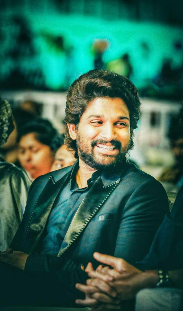 Allu Arjun smiling brightly in a stylish suit charming wallpaper background for fans