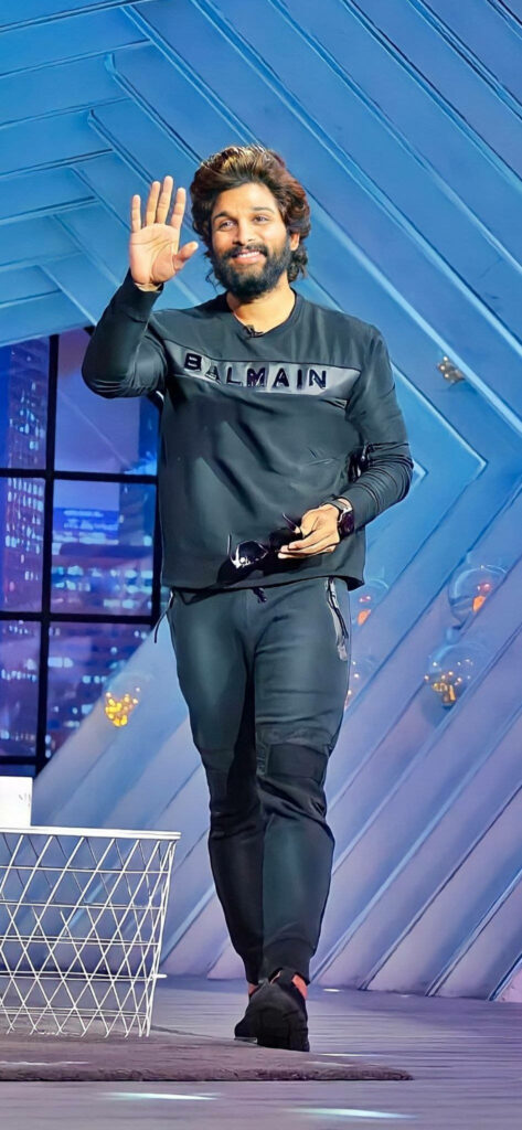 Allu Arjun smiling and waving on stylish stage vibrant wallpaper background for fans and desktop