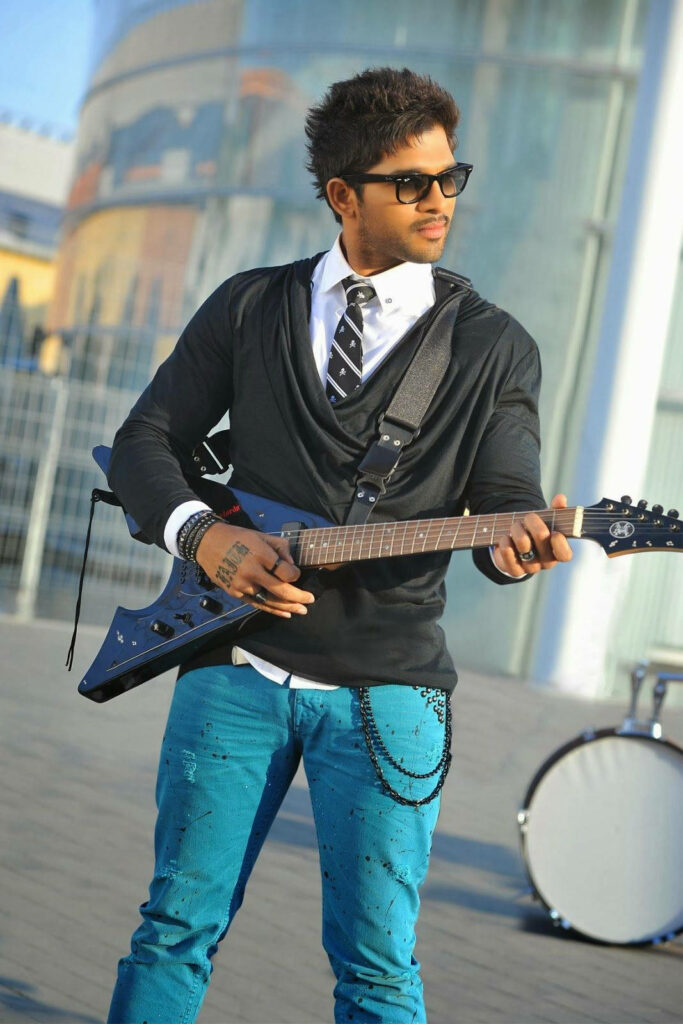 Allu Arjun stylishly playing electric guitar in modern urban backdrop vibrant wallpaper background