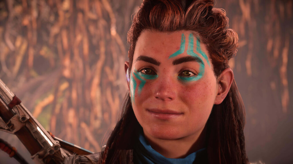 Aloy with blue face paint standing confidently in a lush natural forest wallpaper background