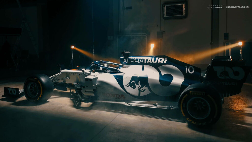 Alphatauri Formula 1 car in dim garage lit to emphasize sleek design and team branding wallpaper
