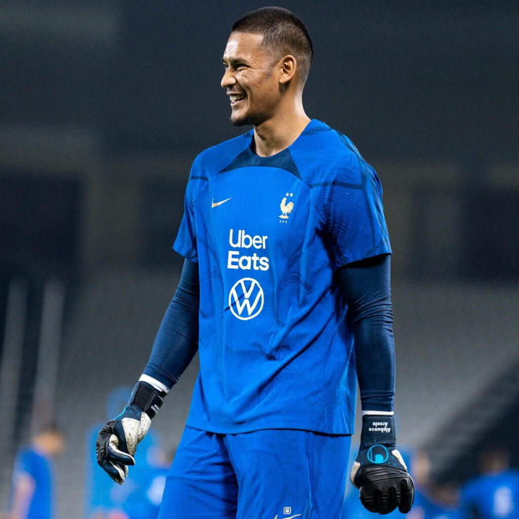 Alphonse Areola in blue goalkeeper uniform smiling confidently on field ready for action wallpaper