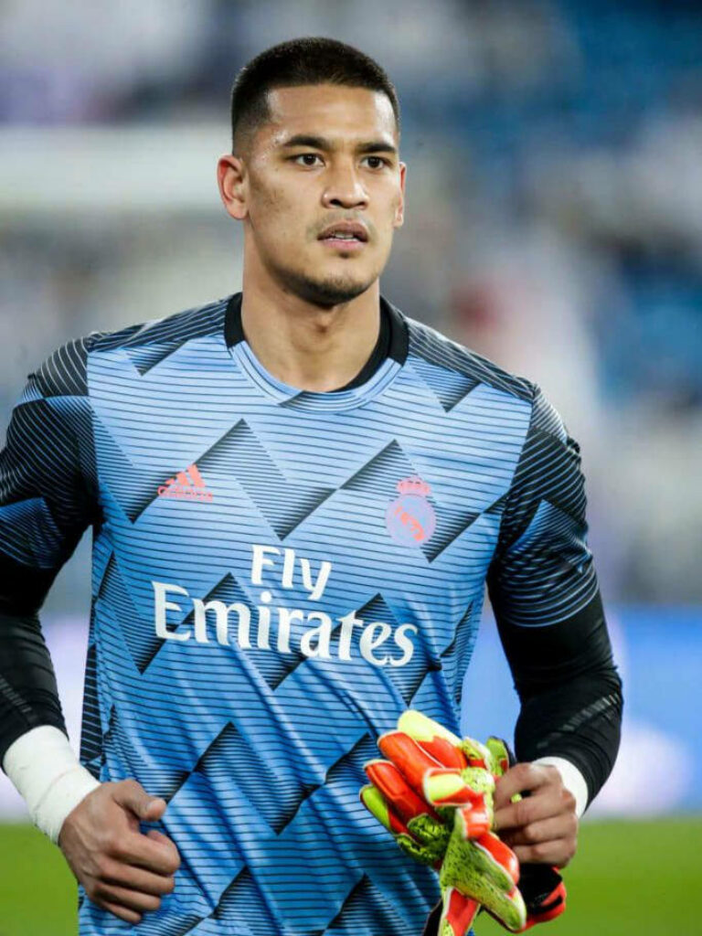 Alphonse Areola close-up in Real Madrid goalkeeper kit with gloves in hand stadium background Wallpaper