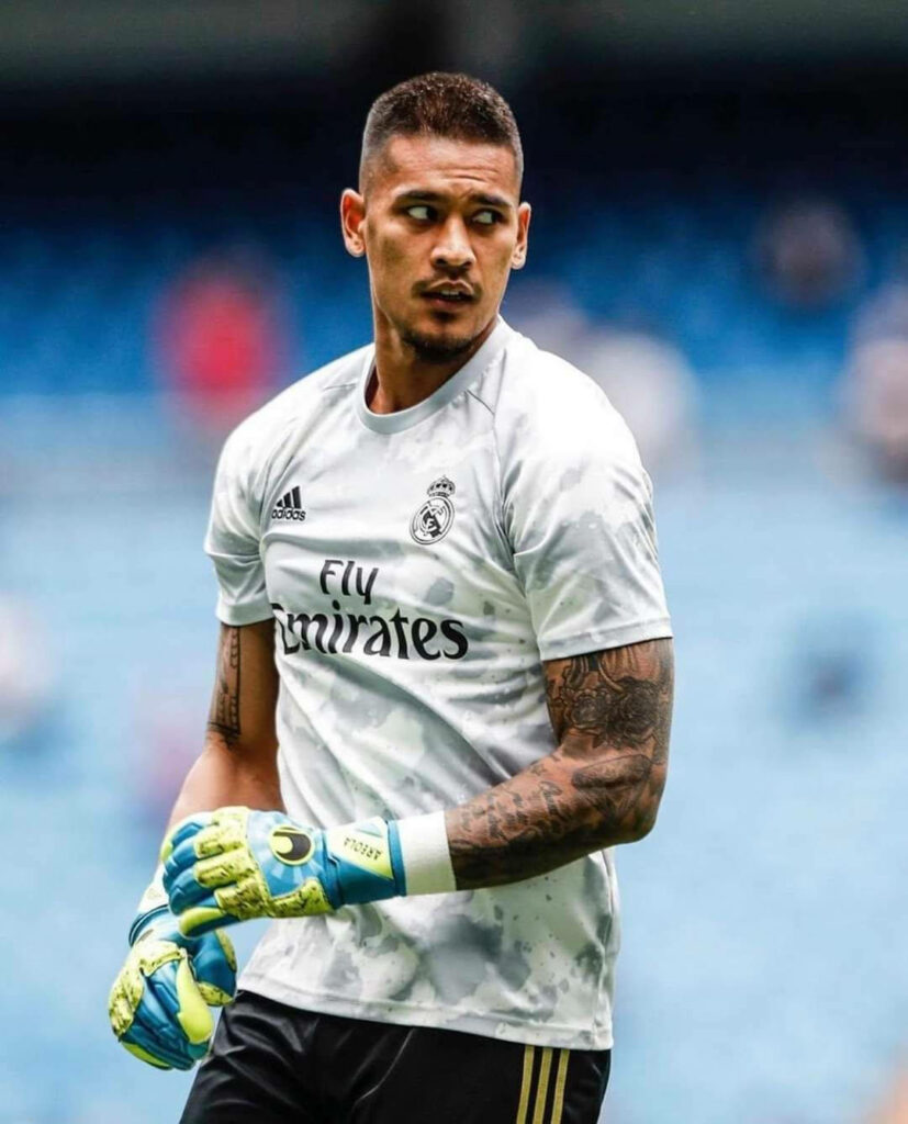 Alphonse Areola in white Real Madrid goalkeeper kit ready focused on football field background Wallpaper