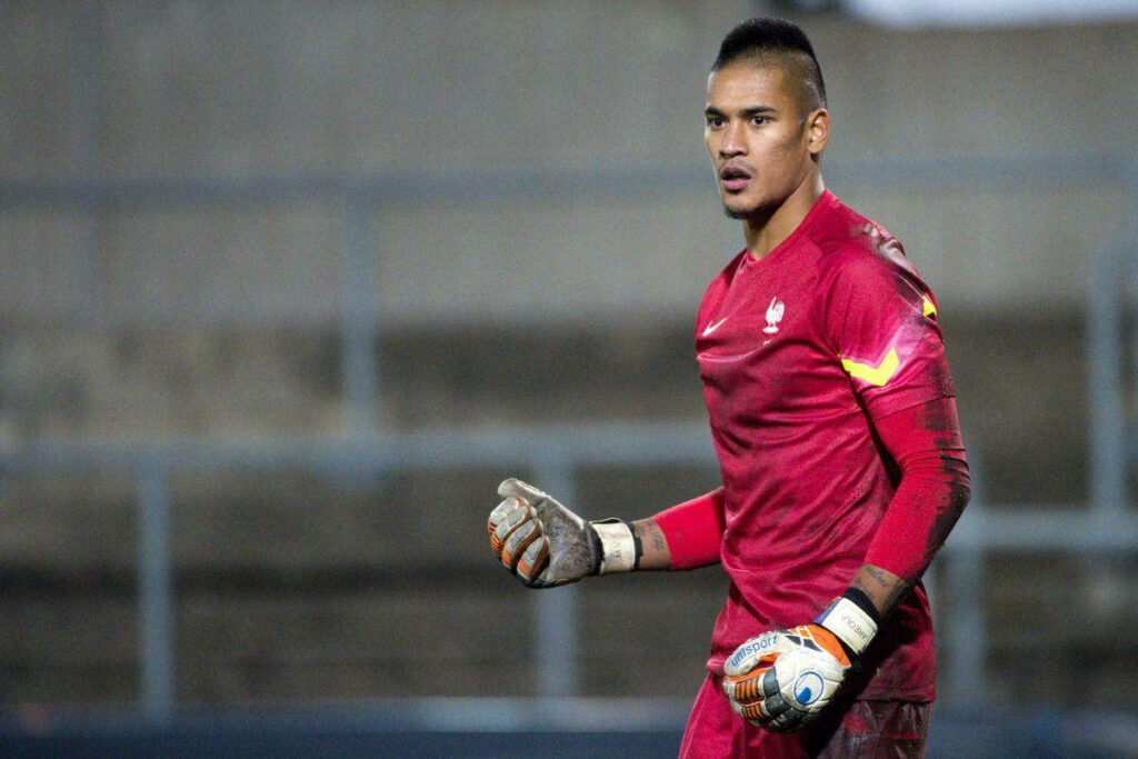 Alphonse Areola focused goalkeeper in red uniform ready to save on soccer field wallpaper background