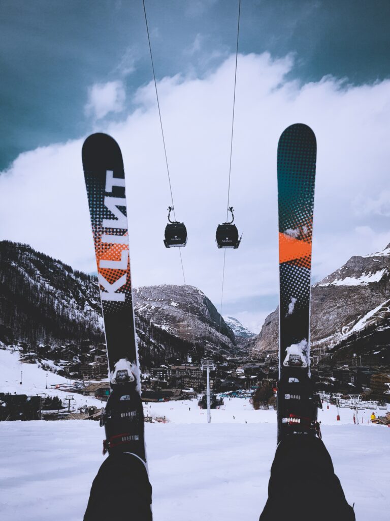 Skier view with bold skis snowy slopes cable car majestic mountains cloudy winter sky wallpaper background