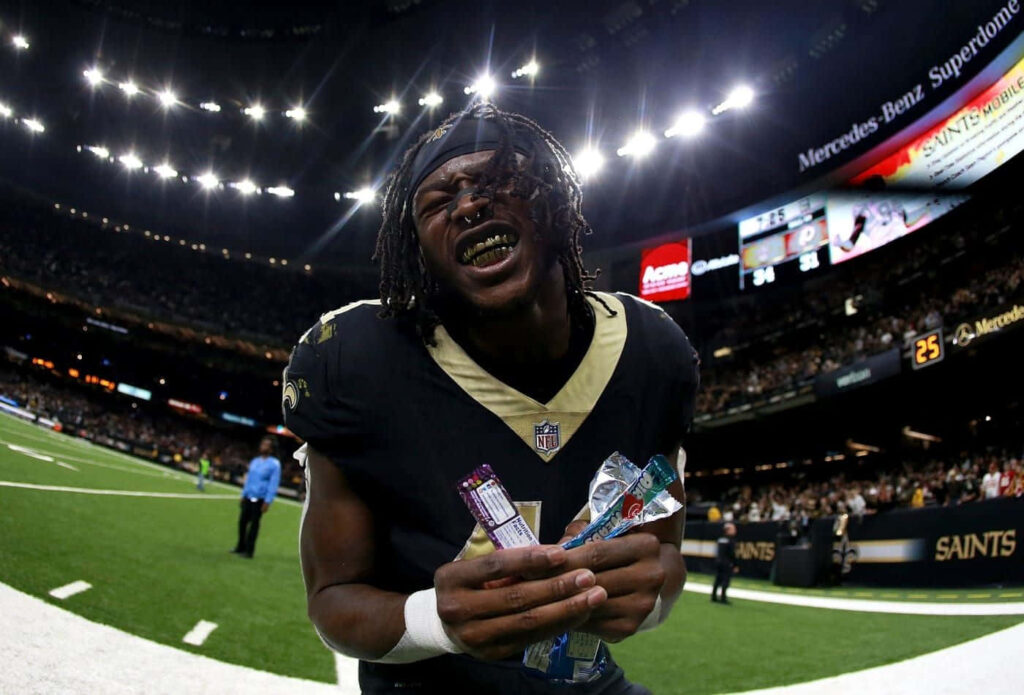 Alvin Kamara New Orleans Saints holding football energized on field with cheering stadium crowd Wallpaper