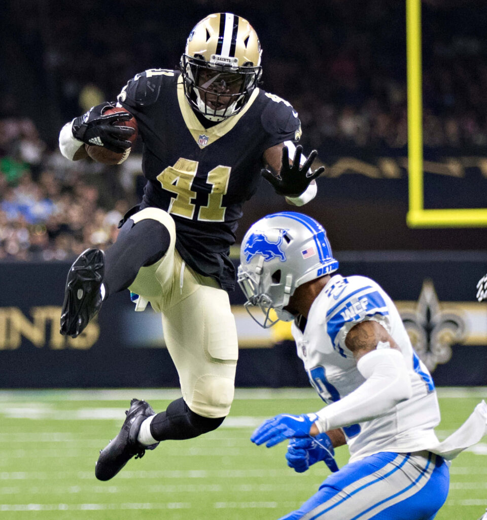 Alvin Kamara jumps over defender running ball for New Orleans Saints NFL game action wallpaper