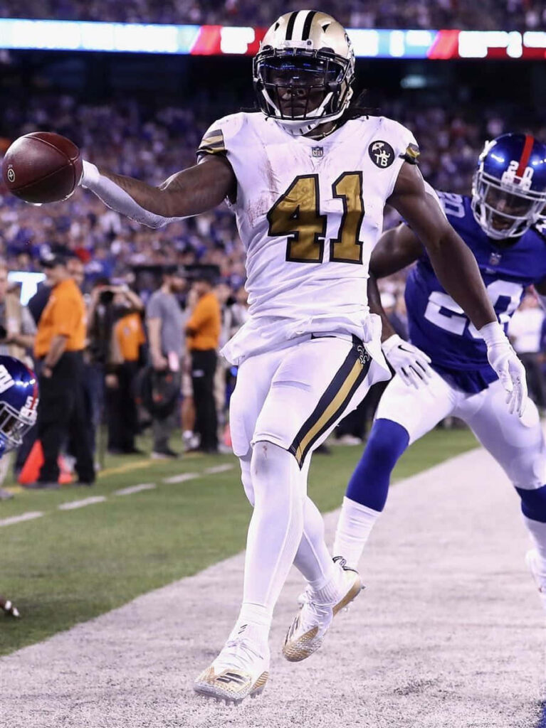 Alvin Kamara sprinting with football in New Orleans Saints uniform chased by NFL defenders Wallpaper