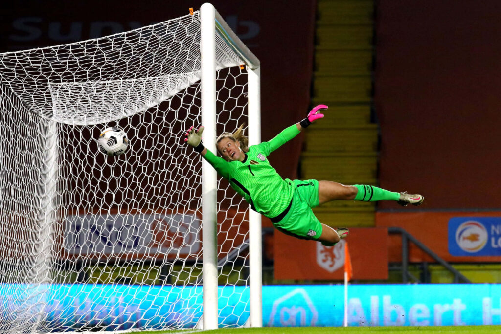 Alyssa Naeher diving save soccer goalkeeper in green kit front of net intense match action Wallpaper