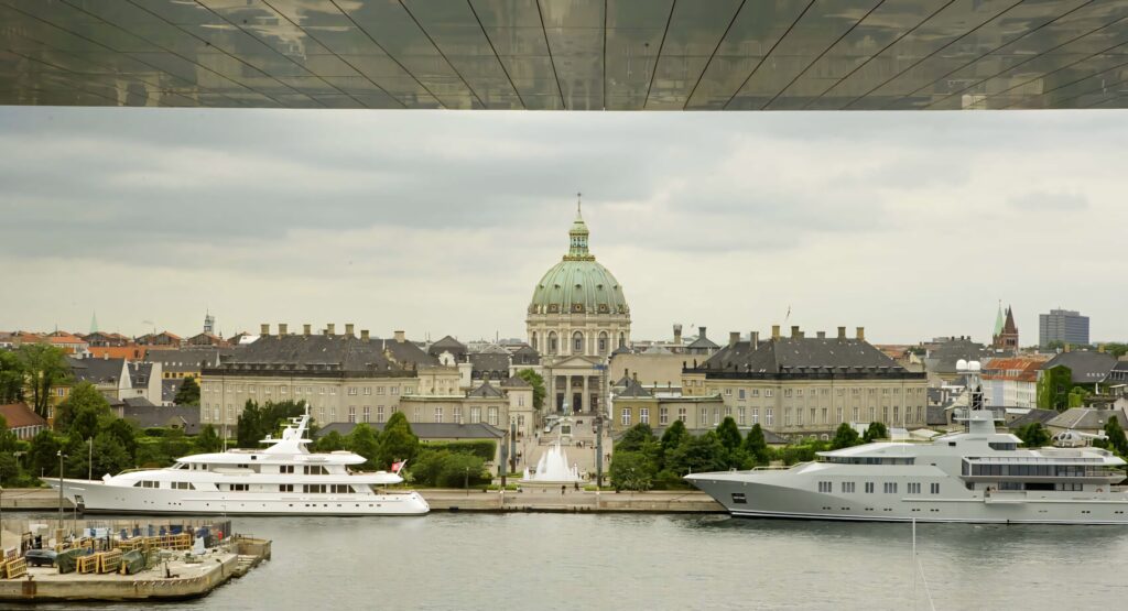 Back view of Amalienborg Palace with Frederik's Church dome and luxury yachts at waterfront Wallpaper