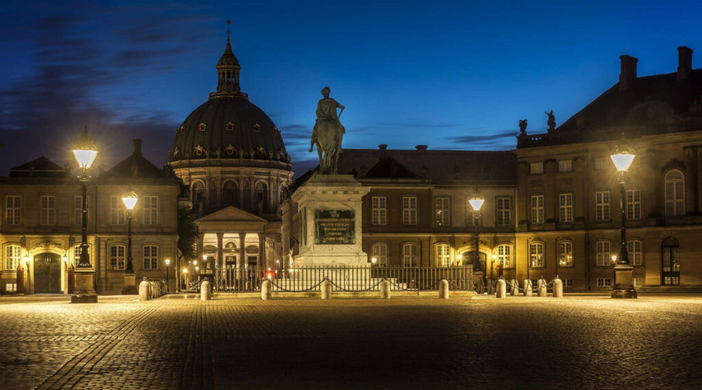 Amalienborg Palace illuminated at night with Frederik’s Church dome and statue under blue sky Wallpaper