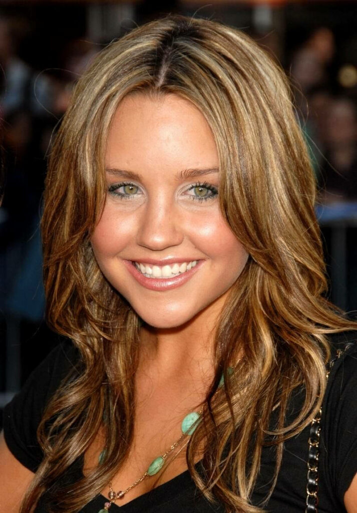 Amanda Bynes with brown eyes and highlighted hair smiling brightly vibrant wallpaper background