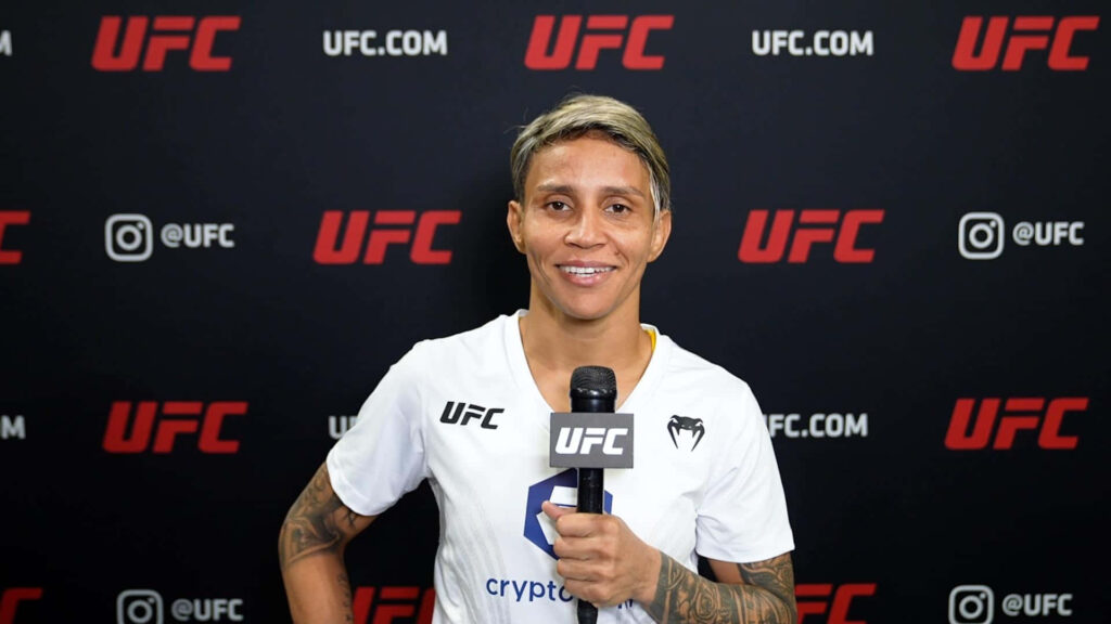 Amanda Lemos confident UFC interview smiling front of branded backdrop vibrant fighter wallpaper