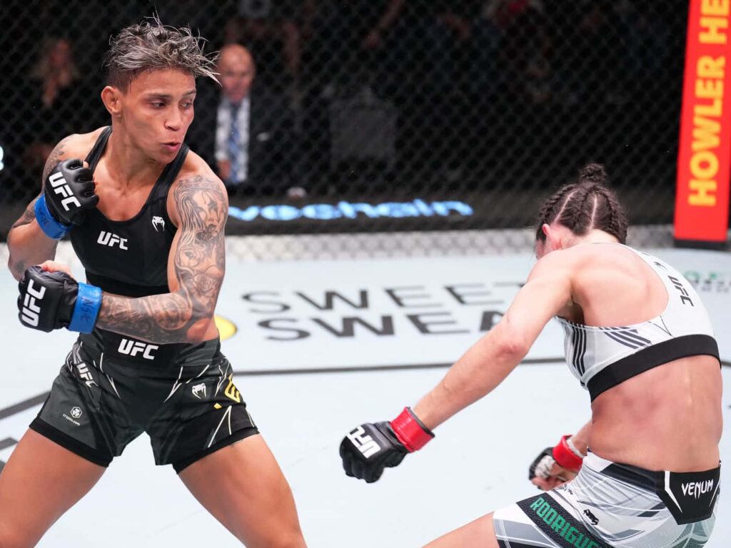 Amanda Lemos dodges punch showing quick reflexes and determination in intense UFC fight octagon Wallpaper