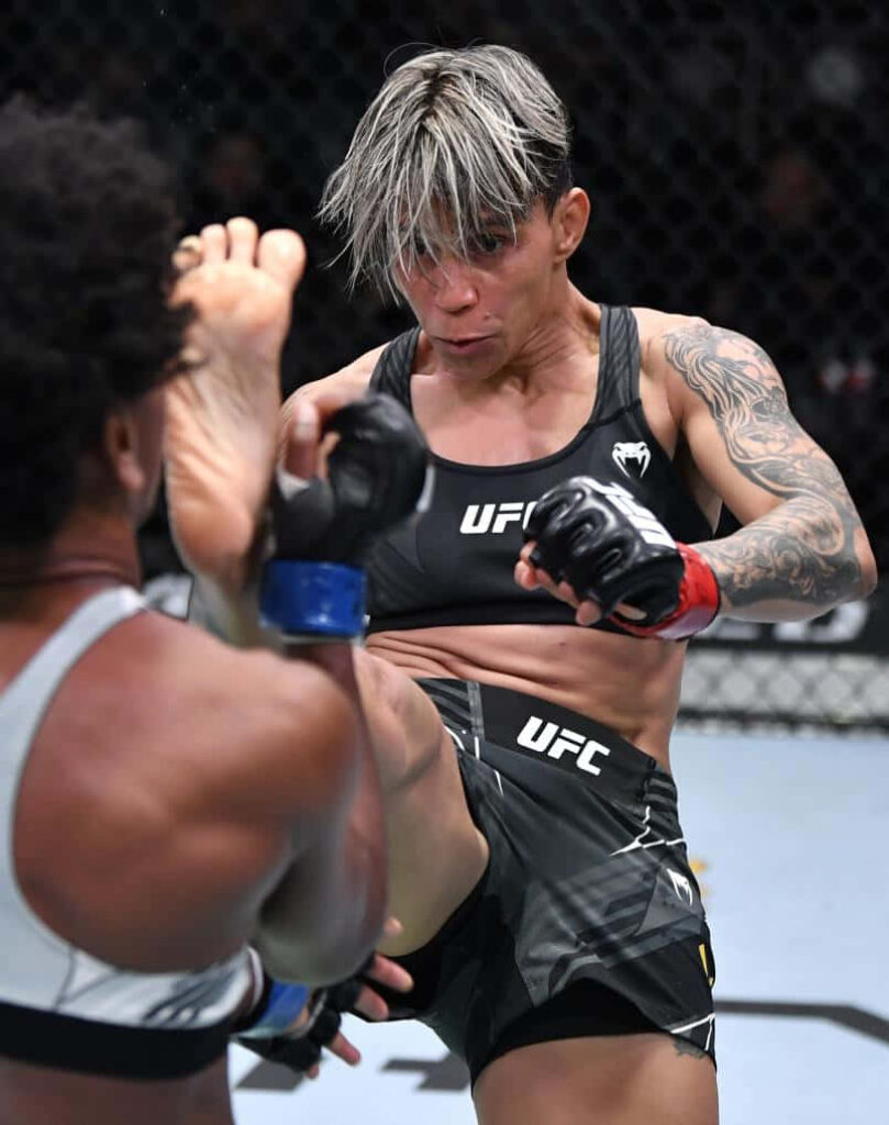 Amanda Lemos delivering a powerful kick in an intense UFC fight showing athleticism and skill Wallpaper
